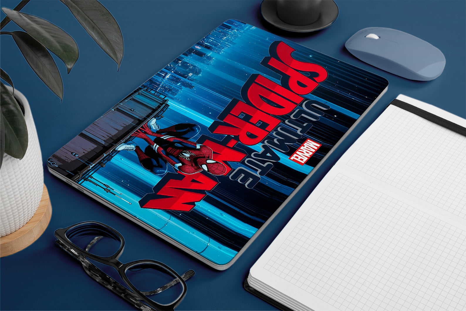 Tablet with a Spider-Man design on a blue surface with office items.