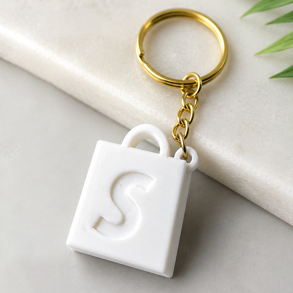 Small 3D printed Shopify keychain with 1 million order milestone text and gold keyring