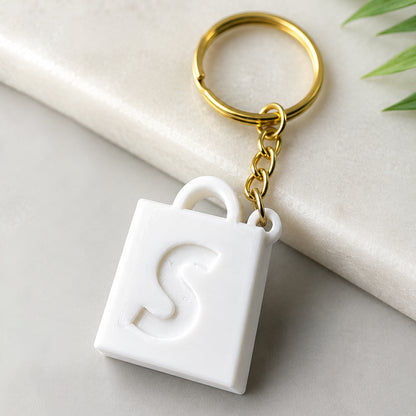 Small 3D printed Shopify keychain with 1 million order milestone text and gold keyring
